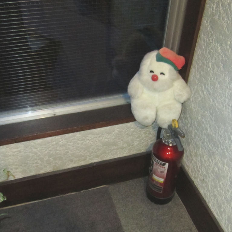 Плюшевая игрушка рядом с огнетушителем в одной из гостиниц; Нагано